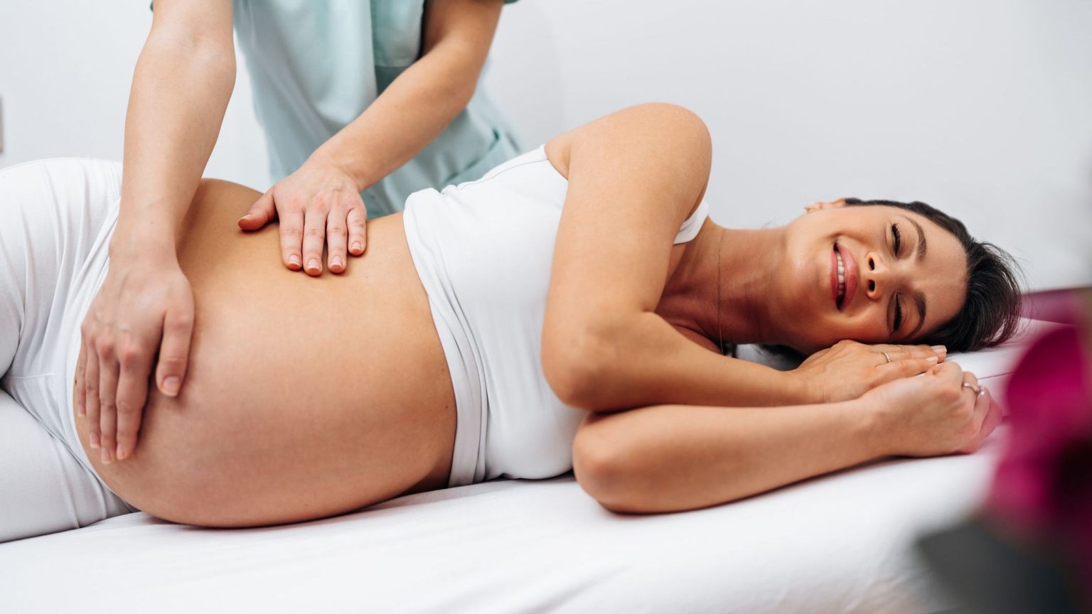 Femme enceinte allongée sur le côté, détendue, pendant un soin chiropratique adapté à la grossesse
