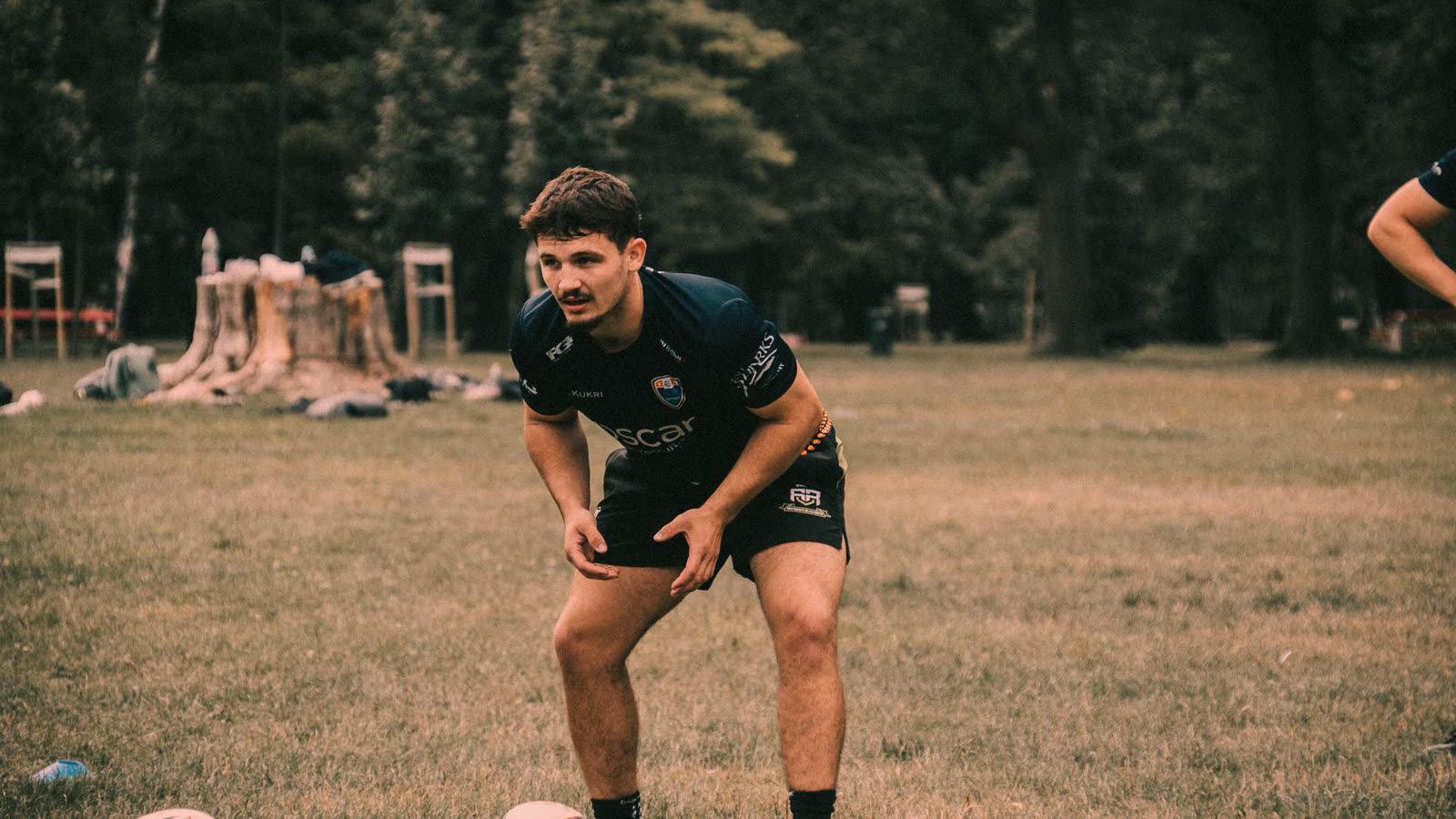 Joueur de rugby amateur à l'entraînement, fléchi sur ses appuis, prêt à changer de direction