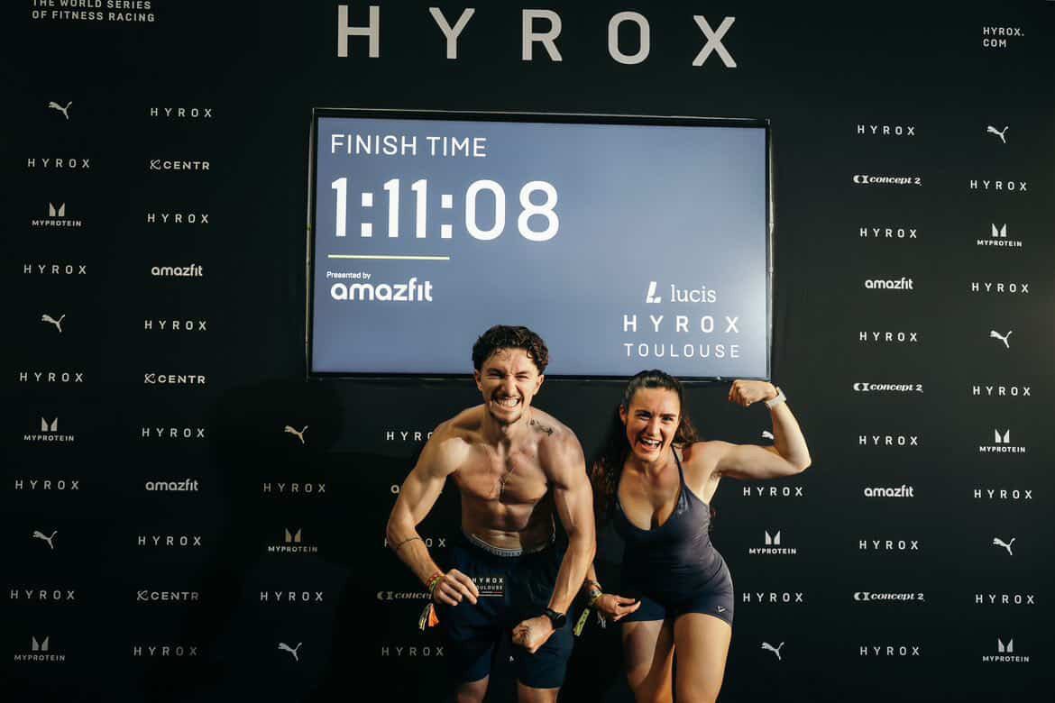 Athlète franchissant la ligne d'arrivée d'une course Hyrox, épuisé et satisfait